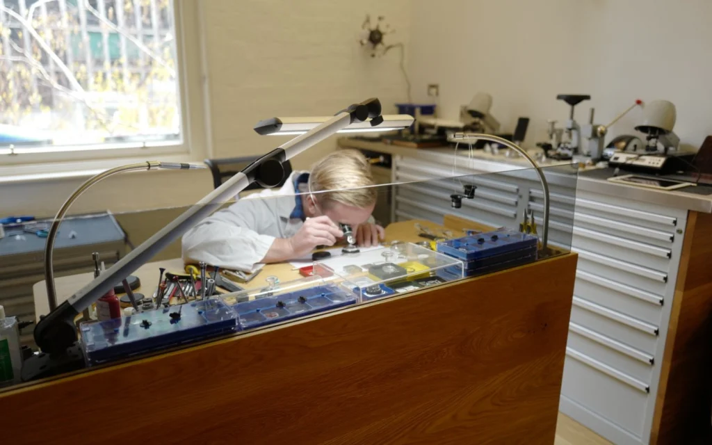 A watchmaker working at a bench in the Watch Collector workshop.