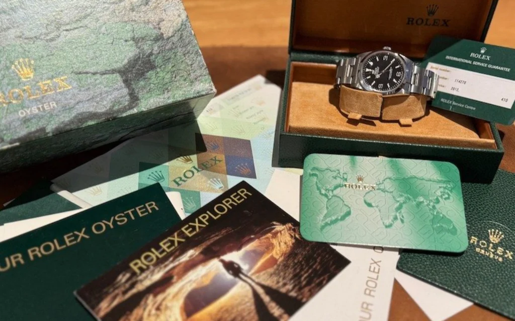 A Rolex watch with its box and accompanying paperwork.